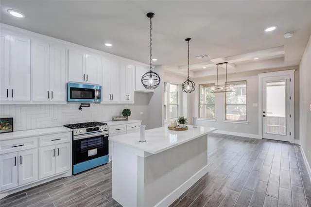 a open kitchen with stainless steel appliances granite countertop a sink a stove and a wooden floors