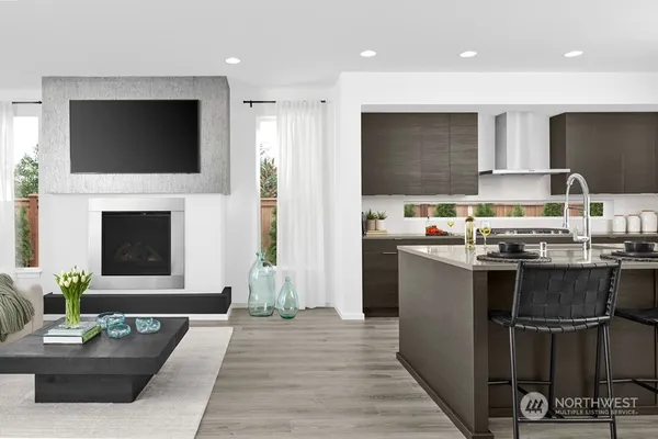 a living room with stainless steel appliances furniture a fireplace a flat screen tv and a fireplace