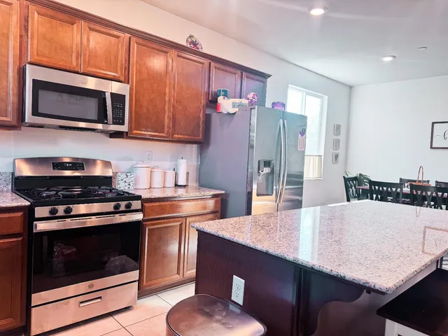 a kitchen with stainless steel appliances granite countertop a stove a microwave a refrigerator a sink and dishwasher