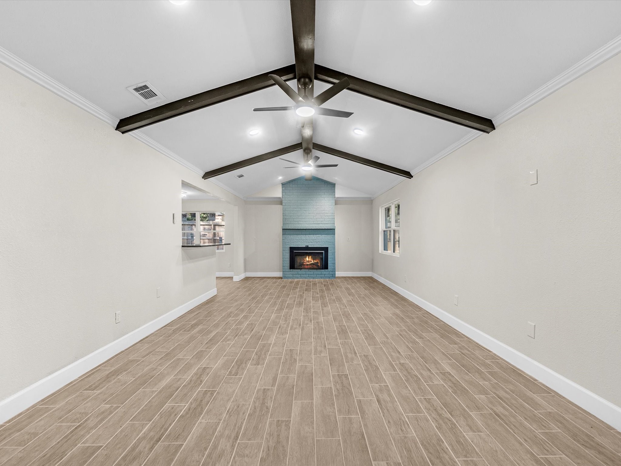 9096 North Comanche Circle Willis, TX 77378 - Photo 8 of 30 Great Room with wood look tile flooring, custom painted fireplace , wood beams and 2 modern fan lighting