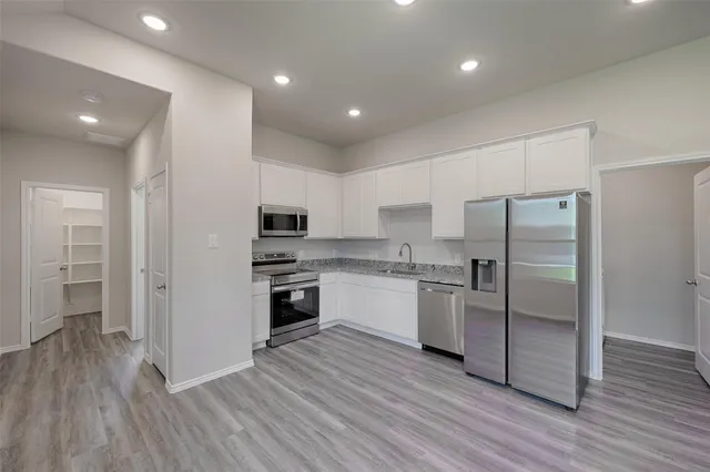a kitchen with stainless steel appliances granite countertop a refrigerator and a stove top oven