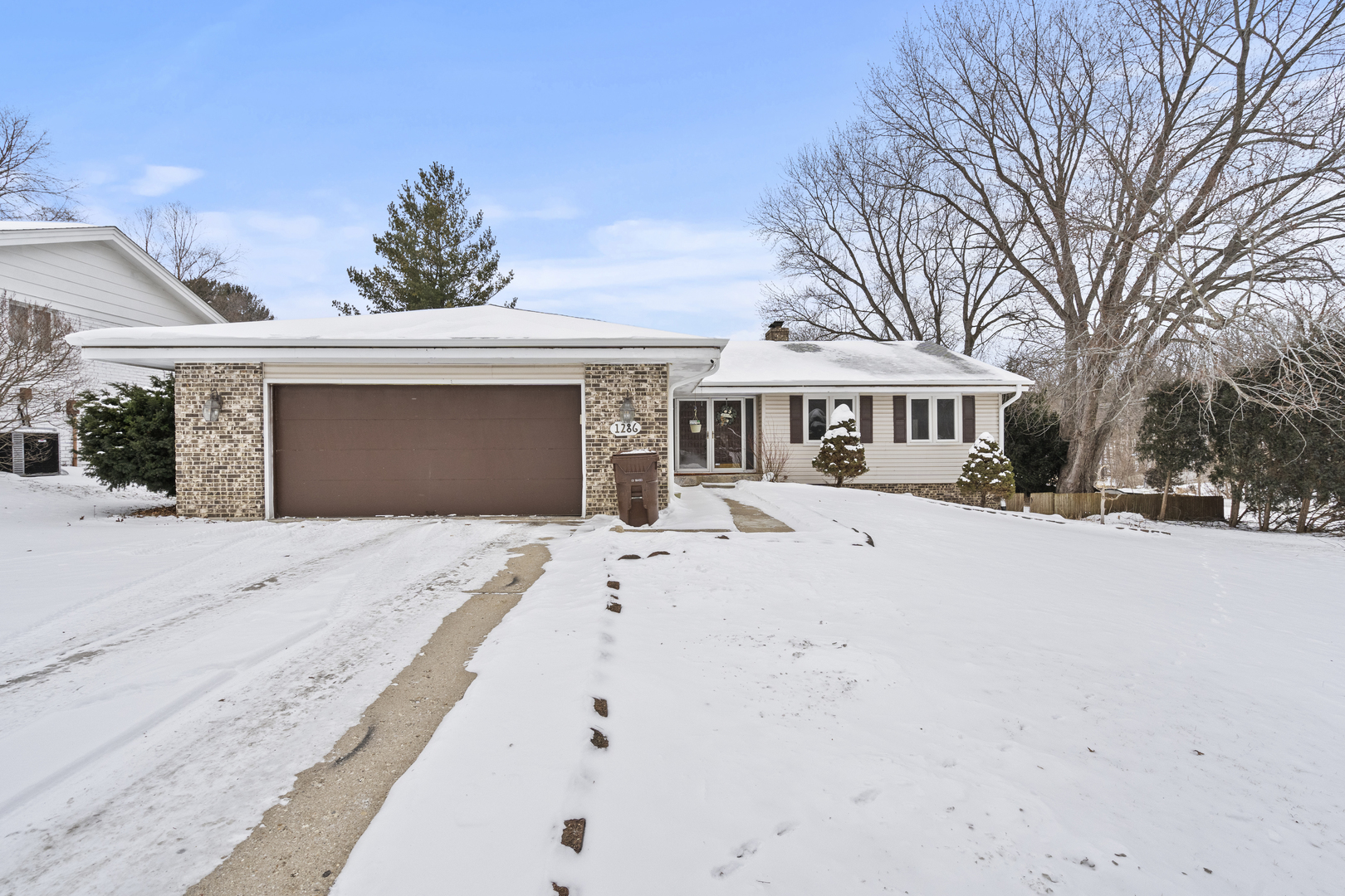 a front view of a house with a yard covered with snow and palm trees