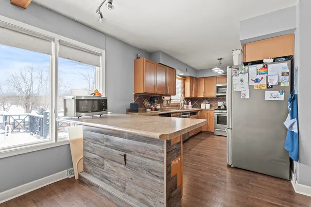 a kitchen with stainless steel appliances granite countertop a refrigerator a stove and a wooden floors