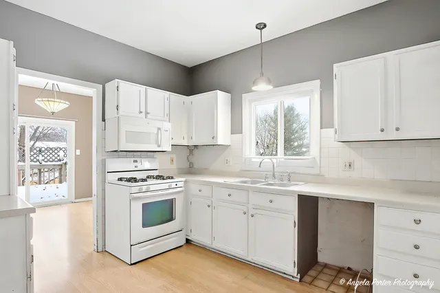 a kitchen with white cabinets appliances and a window