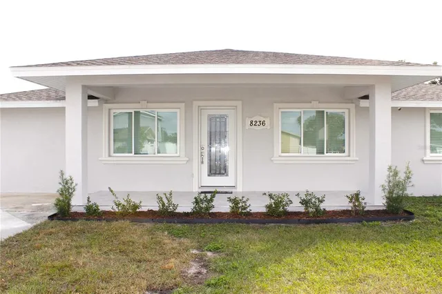 a front view of a house with a large window and potted plants