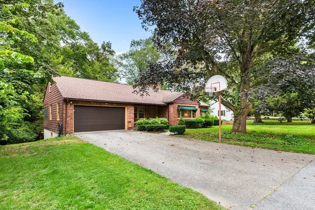 a front view of a house with a garden and trees