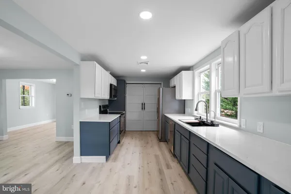 a kitchen with stainless steel appliances granite countertop a stove a sink dishwasher and a refrigerator with wooden floor