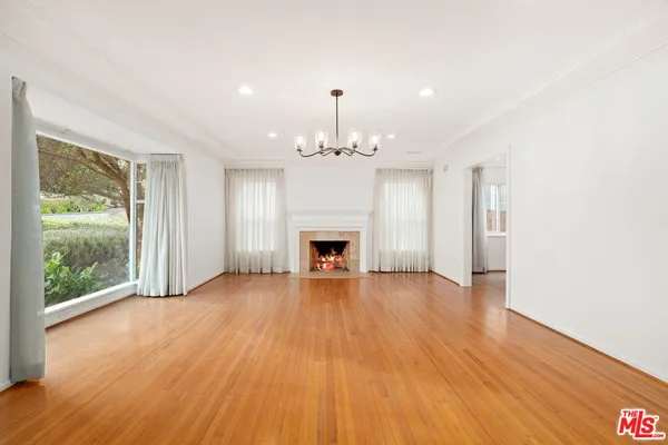 a view of an empty room with wooden floor fireplace and a window