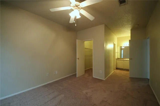 an empty room with a bathroom and a ceiling fan