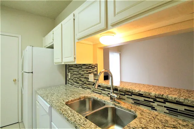 a kitchen with a granite countertop sink and refrigerator