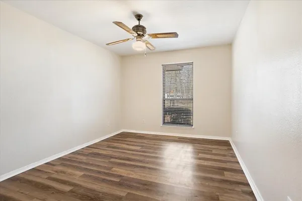 a view of an empty room with wooden floor and a window