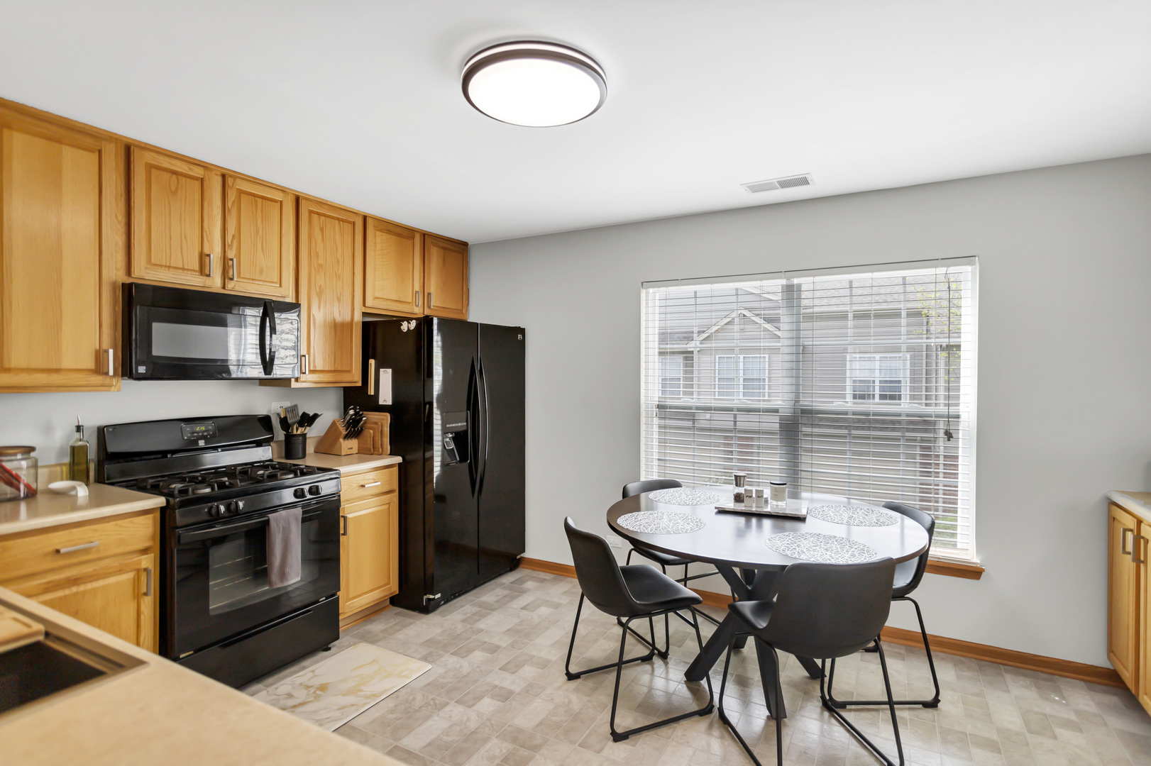 2262 Rockefeller Drive Geneva, IL 60134 - Photo 10 of 25 a kitchen with stainless steel appliances a sink a stove a refrigerator cabinets and a dining table with wooden floor
