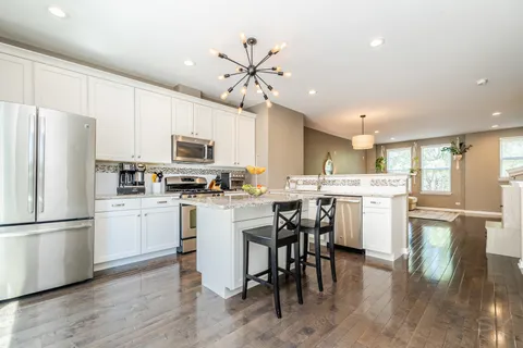 a kitchen with a refrigerator a microwave oven a sink dishwasher with a dining table and chairs