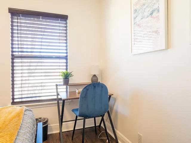 a view of a workspace room with furniture and a window