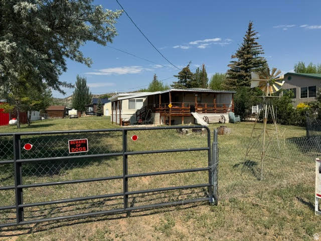 123 North 3rd Manila, UT 84046 - Photo 1 of 15 Expansive property featuring a chain-link fence and metal gate, a large yard with mature trees, and a visible windmill structure