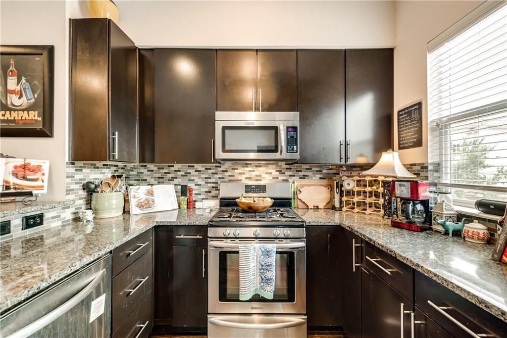 3200 Ross Avenue, Unit 31 Dallas, TX 75204 - Photo 6 of 13 Kitchen featuring appliances with stainless steel finishes, dark brown cabinets, tasteful backsplash, and light stone counters