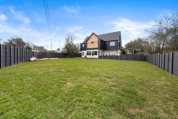 a view of a house with a yard and fence