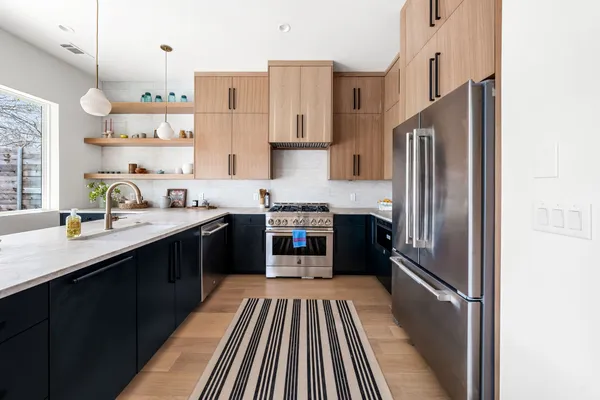 a kitchen with stainless steel appliances granite countertop a refrigerator a sink dishwasher a stove and white cabinets with wooden floor