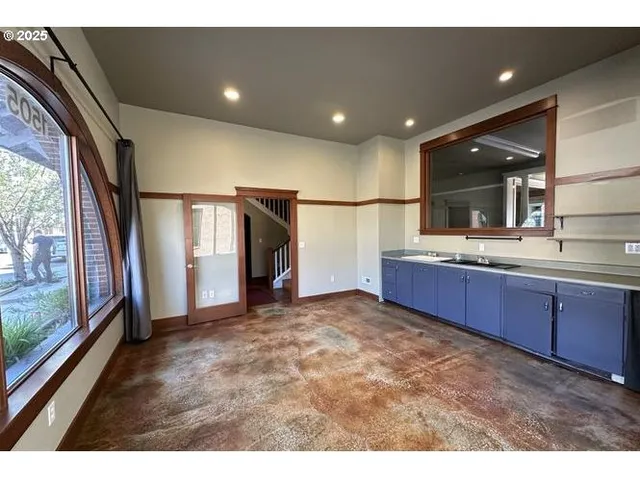 a living room with stainless steel appliances kitchen island granite countertop a refrigerator a sink and a large window