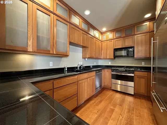 a kitchen with stainless steel appliances granite countertop a stove a sink and a microwave