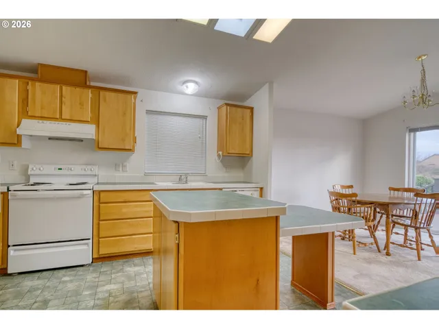 a kitchen with stainless steel appliances granite countertop a sink a stove cabinets counter space and a window