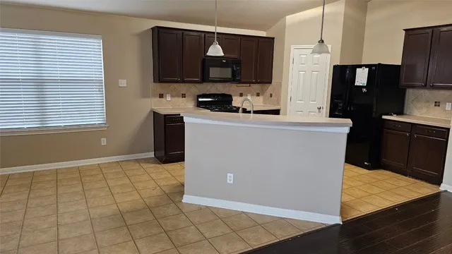 a kitchen with stainless steel appliances a stove a refrigerator a sink a counter space and cabinets