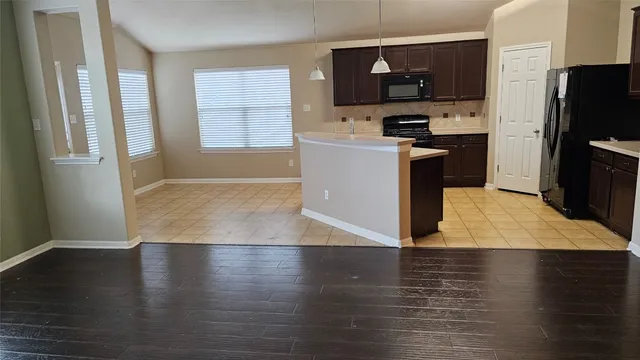 a kitchen with stainless steel appliances granite countertop a refrigerator a sink a stove top oven a counter space and cabinets