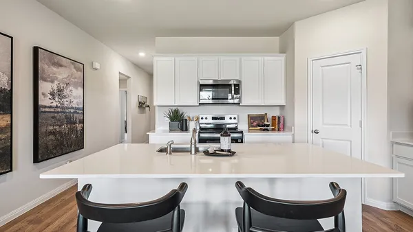 a kitchen with stainless steel appliances a stove a refrigerator a sink and white cabinets with wooden floor