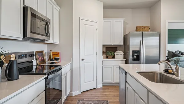 a kitchen with a refrigerator a stove a sink and white cabinets with wooden floor