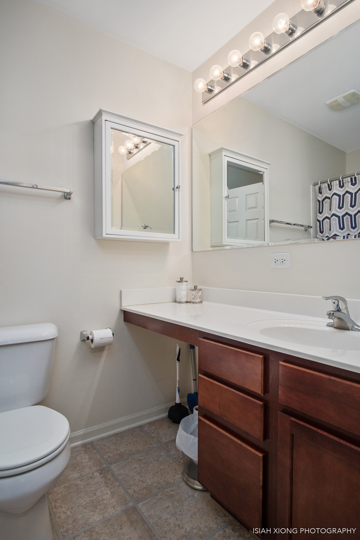 445 Dancer Lane, Unit 405 Oswego, IL 60543 - Photo 12 of 32 a bathroom with a toilet a sink and mirror