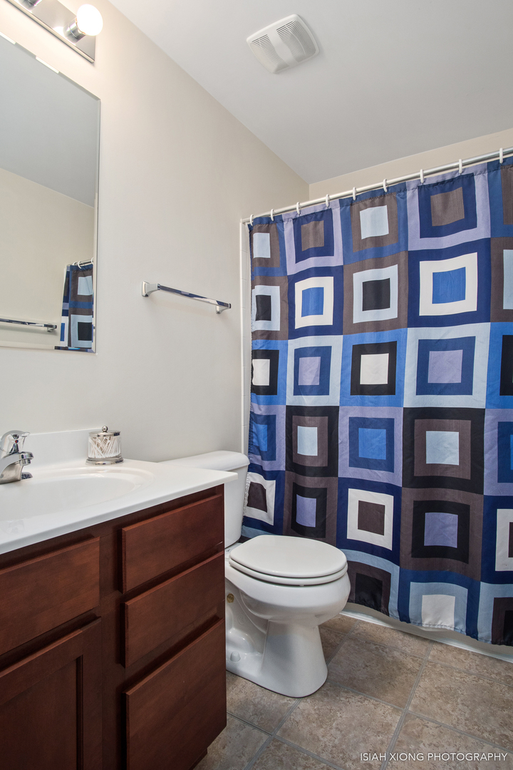 445 Dancer Lane, Unit 405 Oswego, IL 60543 - Photo 14 of 32 a bathroom with a toilet a sink and a large mirror