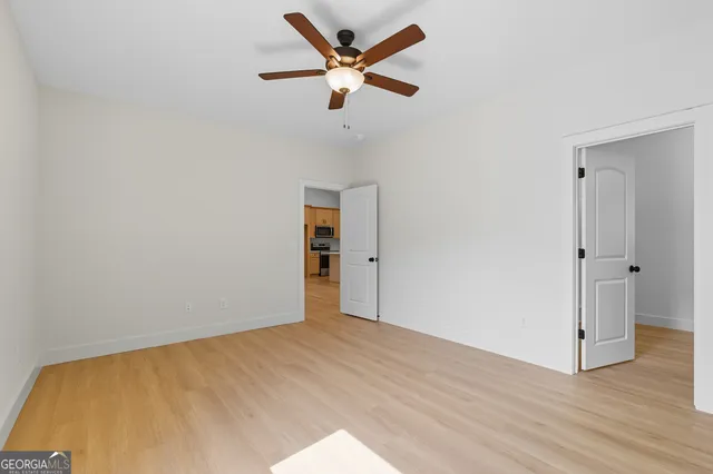 an empty room with wooden floor and ceiling fan