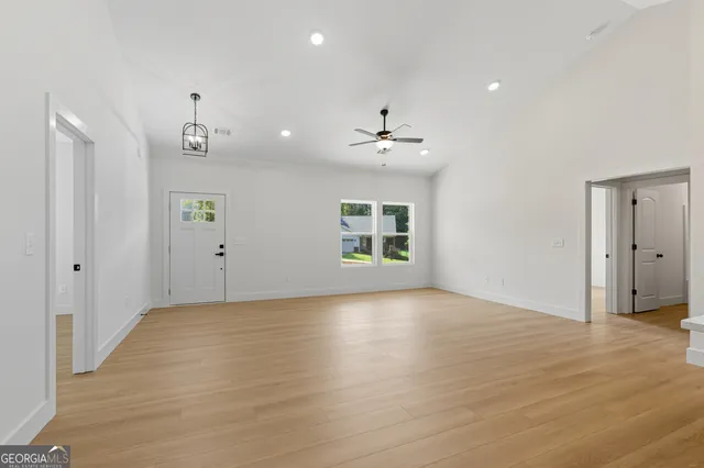 a view of an empty room with a window and wooden floor
