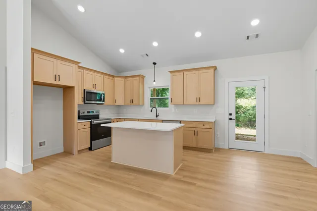 a large kitchen with stainless steel appliances granite countertop a stove a sink dishwasher and a refrigerator with wooden floor