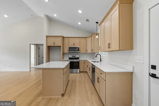 a kitchen with stainless steel appliances a sink a stove a refrigerator cabinets and a center island