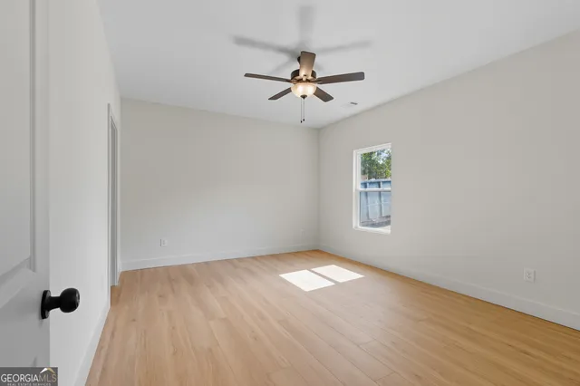 an empty room with wooden floor fan and windows
