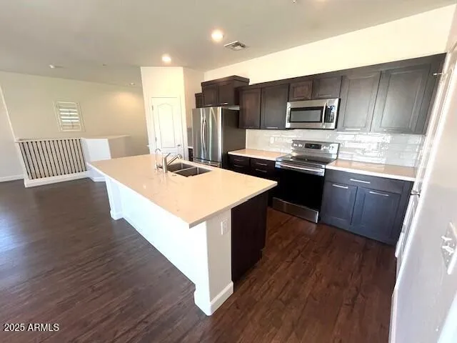 a kitchen with stainless steel appliances kitchen island granite countertop a stove a sink a refrigerator and a microwave