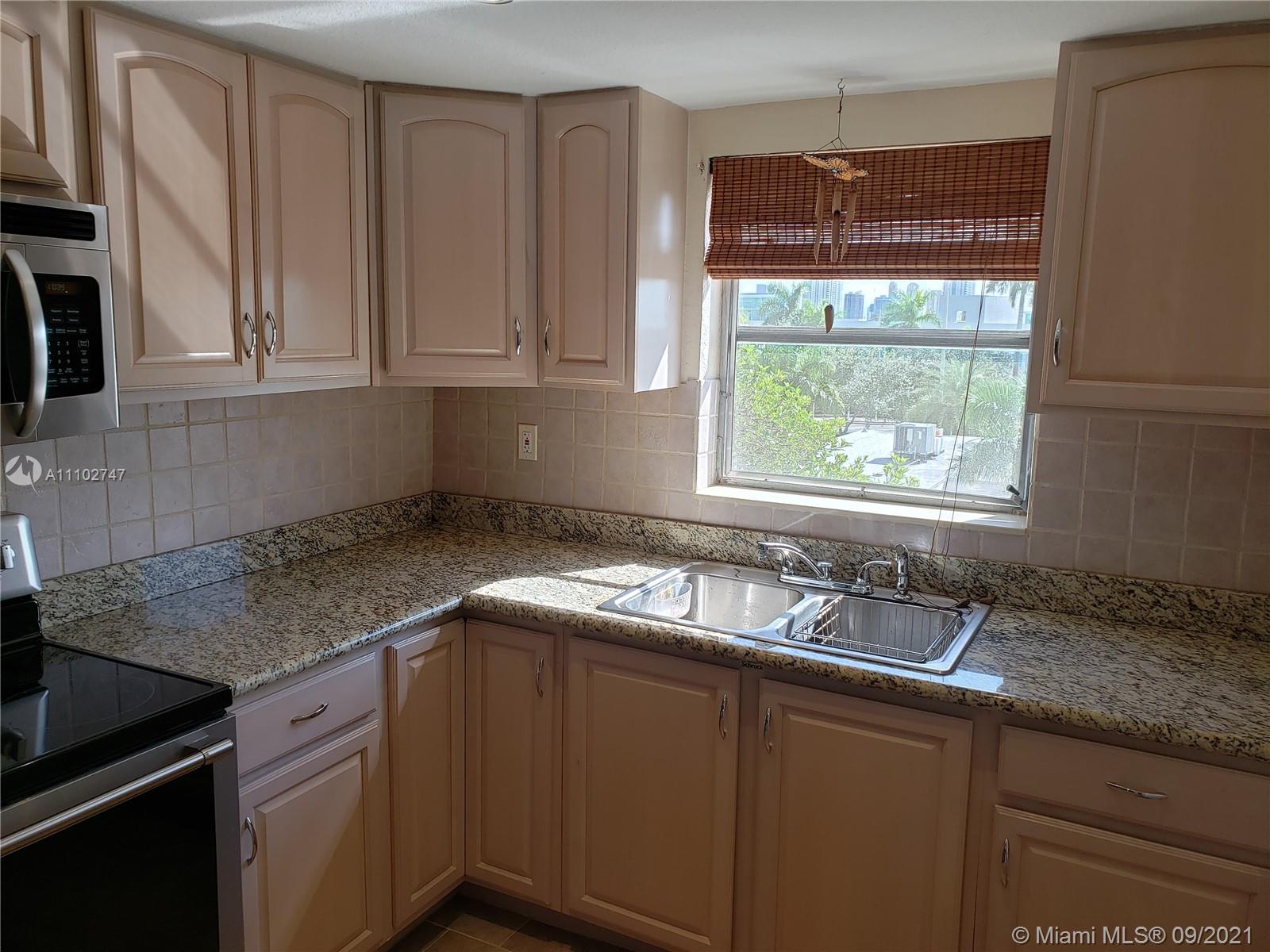 a kitchen with granite countertop stainless steel appliances window a sink and a counter space