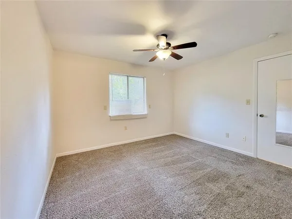 an empty room with windows and fan