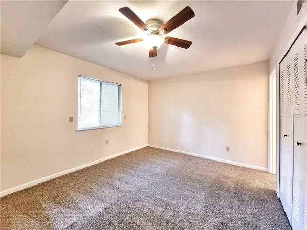 an empty room with ceiling fan and windows