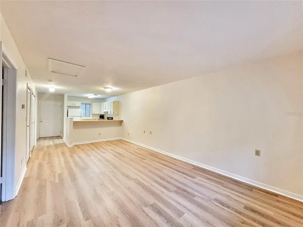a view of kitchen and empty room with wooden floor