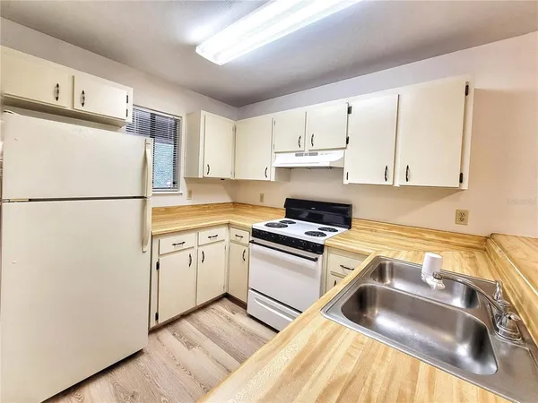 a kitchen with a refrigerator sink and white cabinets