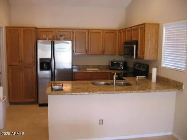 a kitchen with stainless steel appliances granite countertop a refrigerator a stove and a sink with wooden cabinets