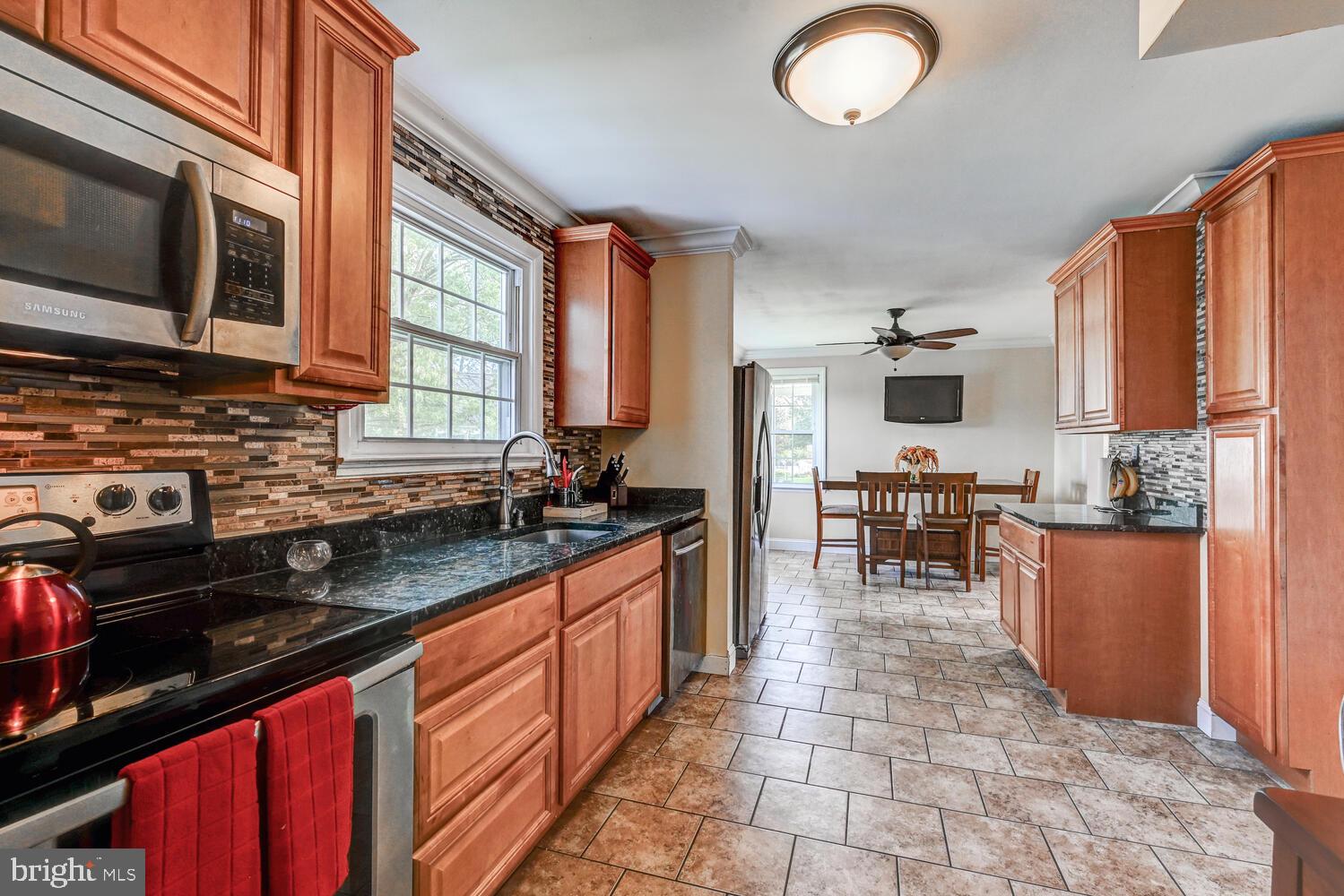 2636 Spring Road Baltimore, MD 21234 - Photo 11 of 25 a kitchen with stainless steel appliances granite countertop a stove top oven a sink dishwasher a dining table and chairs with wooden floor