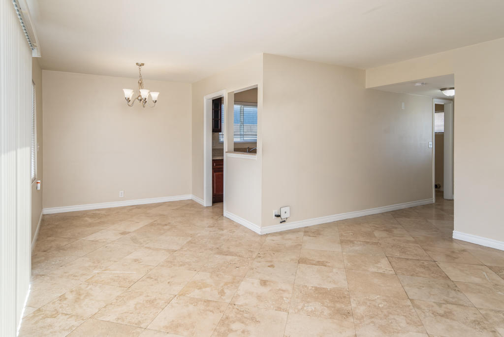 45546 3rd Street East Lancaster, CA 93535 - Photo 6 of 23 an empty room with kitchen view and a chandelier fan