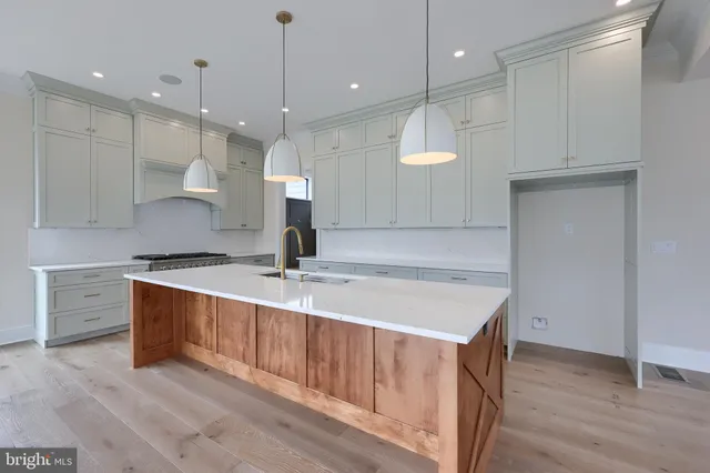 a large kitchen with kitchen island a large counter top space a sink stainless steel appliances and cabinets