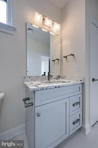 a spacious bathroom with a granite countertop sink a mirror and a bathtub