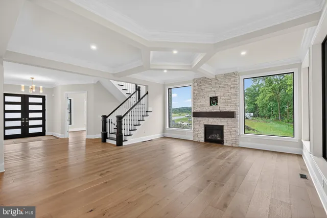 a view of an empty room with wooden floor windows and a fireplace