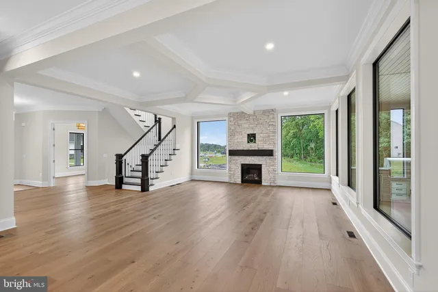 a view of an empty room with wooden floor a fireplace and windows