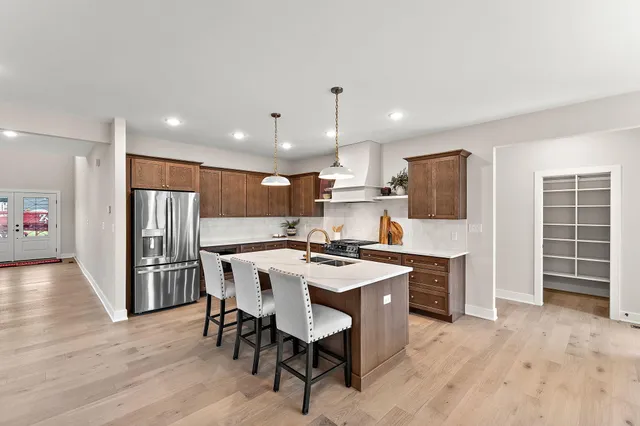 a kitchen with stainless steel appliances a dining table chairs stove refrigerator and cabinets